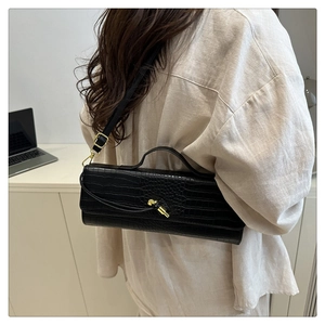 Detail of black crocodile texture handbag with gold knot hardware and adjustable strap