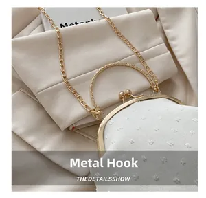 Primer plano de los ganchos metálicos dorados y la tela jacquard blanca del bolso elegante