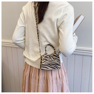 Detail view of zebra print crossbody bag on a model featuring sleek strap and elegant pattern