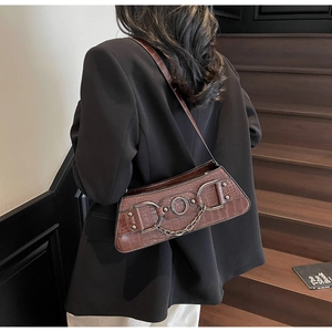 Brown crocodile embossed underarm bag with metal chain detail worn with black suit