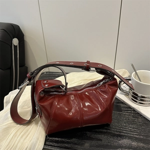Deep red glossy hobo bag with adjustable wide shoulder strap and metallic eyelets