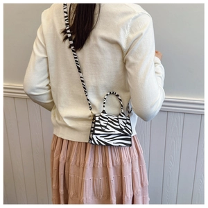 Mini zebra print crossbody bag styled with a white sweater and pink pleated skirt