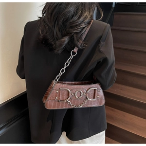 Brown crocodile pattern shoulder bag with silver chain and horsebit detail on wood stairs