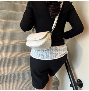 Detail of white PU leather saddle bag with magnetic flap and adjustable strap on a shoulder