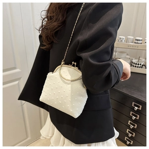 Detail of white textured shell bag with golden chain strap and vintage metal clasp