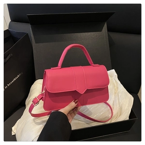 Close-up of rose pink leather handbag with V-shaped buckle in a luxury gift box