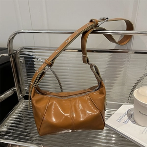 Brown glossy faux leather shoulder bag with silver eyelets and structured design