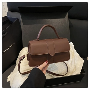 Detail of dark brown faux leather square handbag with V-shaped flap and top handle