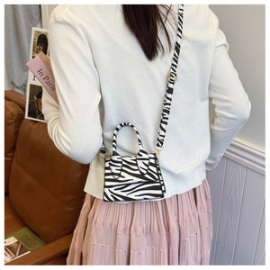 Detailed back view of a mini zebra print crossbody bag styled on a female model