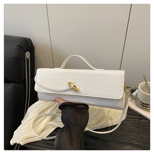 Detail of white crocodile pattern handbag featuring a gold metallic buckle and sleek handle