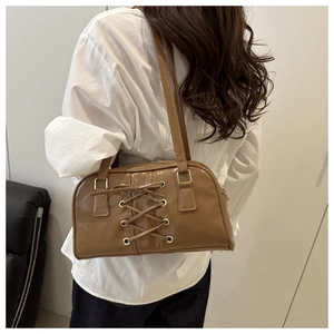 Detail of a brown PU leather shoulder bag featuring decorative lace-up bow and metal eyelets