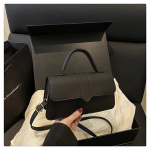 Detail of black matte leather handbag with structured flap and pointed buckle design