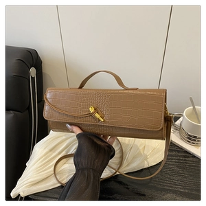 Close-up of caramel brown baguette bag featuring crocodile embossed texture and gold lock