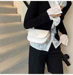 Minimalist white patent leather shoulder bag detail with flap closure on model