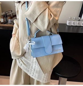 Detail of light blue patent leather crossbody bag with pearl lace bow charm