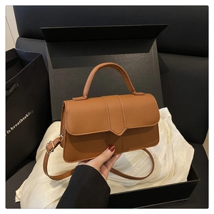 Detail of a brown leather crossbody bag shown with premium gift box and carrier bag