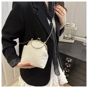 Detail of white vintage kiss-lock bag with 3D dotted texture and golden chain