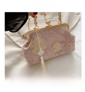 Detail of pink floral jacquard evening bag with golden clasp and beaded tassels