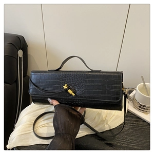 Close-up of black crocodile pattern leather handbag with elegant gold metal buckle