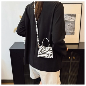 Close-up of mini zebra print crossbody bag styled with a modern black blazer and shorts
