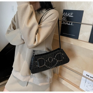 Detail of black crocodile pattern underarm bag with vintage metal rings and chains