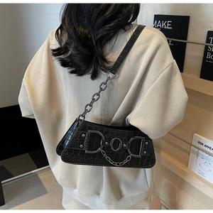 Detail of black faux leather underarm bag with crocodile pattern and silver chain