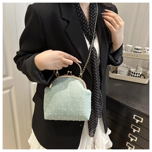 Detail of mint green textured evening bag with gold handle and delicate chain strap