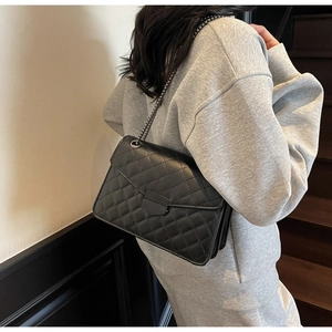 Détail du sac bandoulière noir matelassé avec fermoir bouclier et bandoulière chaîne