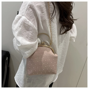 Sac bandoulière rose en tissu texturé avec poignée dorée porté par un modèle