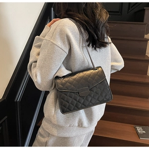Détail du sac en cuir matelassé noir avec bandoulière chaîne et fermoir rectangulaire
