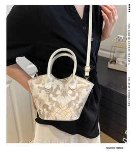 Close-up of white crossbody bag featuring intricate grey and yellow floral embroidery