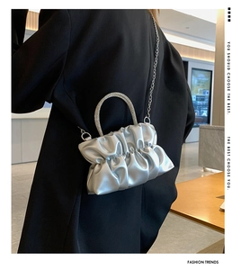 Detail of silver pleated cloud bag featuring rhinestone handle and metal chain strap
