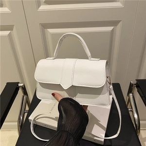 Elegant white leather crossbody handbag with round handle and minimalist square flap design
