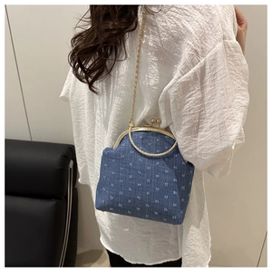 Close-up of retro denim kiss-lock bag with white polka dots and gold chain strap
