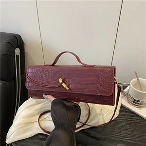 Burgundy crocodile pattern handbag with gold knot buckle and top handle shown in use