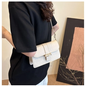 Détail du sac beige avec texture crocodile et fermoir en bambou doré élégant