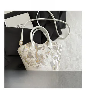 Detailed view of beige floral embroidery handbag with leather trim and size comparison