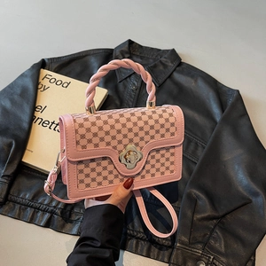 Pink rectangular crossbody bag with floral pattern and golden metal handle on black jacket