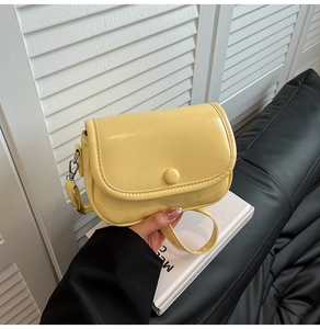 Detailed close-up of cream yellow PU leather handbag with smooth finish and round buckle