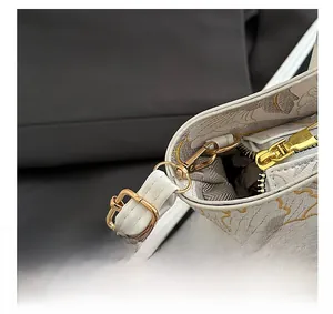 Detail of white leather bucket bag with floral patterns and gold-tone metal hardware