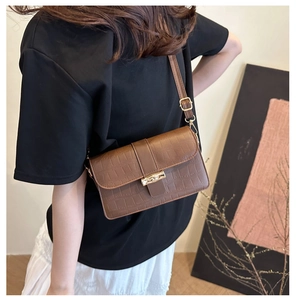 Detail of vintage brown crocodile textured crossbody bag with gold hardware buckle