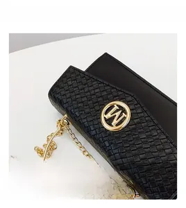 Detail of black woven handbag featuring a gold W logo and circular metal ring handle
