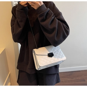 Détail d'un sac à main blanc matelassé avec fermoir noir et bandoulière chaîne