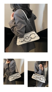 Close-up of white crocodile embossed underarm bag with black metal chain and geometric design