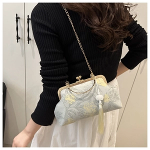 Close-up of light blue floral embroidery and golden metal clasp on women's handbag