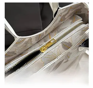 Macro view of golden metal zipper and floral embroidery detail on women's tote bag