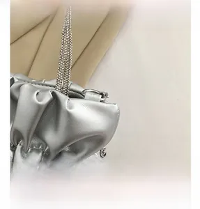 Detailed macro view of silver pleated leather bag with rhinestone handle and metal chain