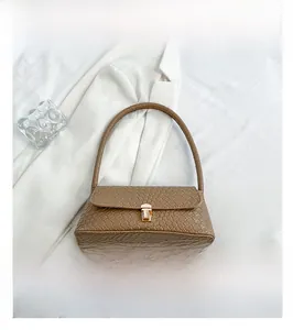 Detail of brown woven faux leather baguette bag with a gold metal clasp on white fabric