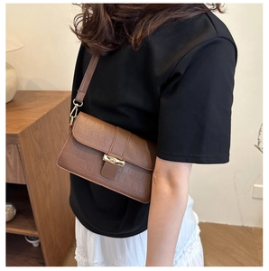 Detailed close-up of brown crocodile pattern shoulder bag with a gold metal lock