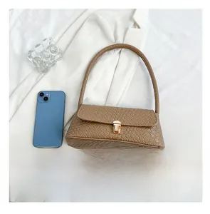 Brown woven baguette bag detail showing size comparison with a smartphone on white fabric